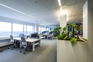 Modern kantoorinterieur aan de Johan Huizingalaan met werkplekken, grote ramen en kamerplanten.